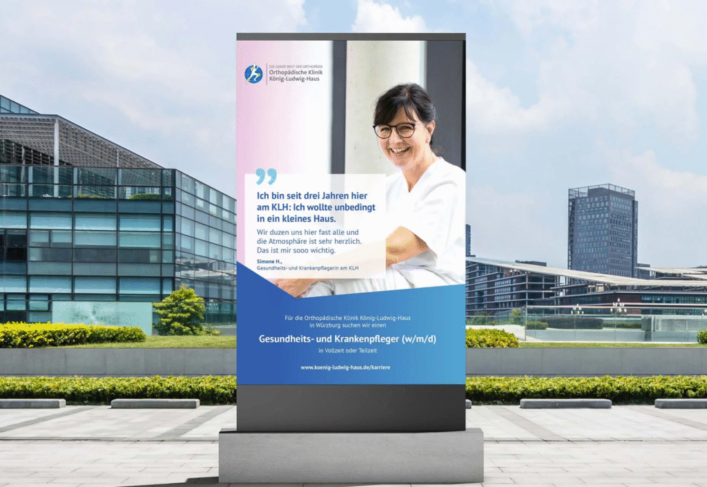 Großes Outdoor-Plakat der Orthopädischen Klinik König-Ludwig-Haus mit einem Foto einer lächelnden Pflegekraft und einem persönlichen Zitat über die herzliche Atmosphäre im KLH.
