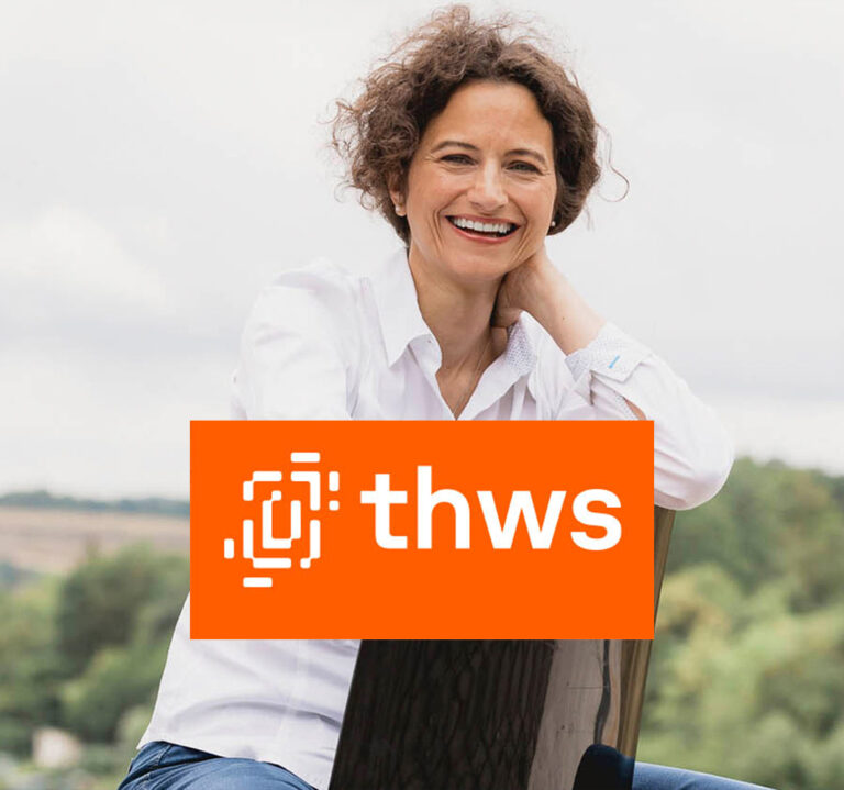 Frau sitzt lächelnd im Freien mit Laptop – THWS Employer Branding