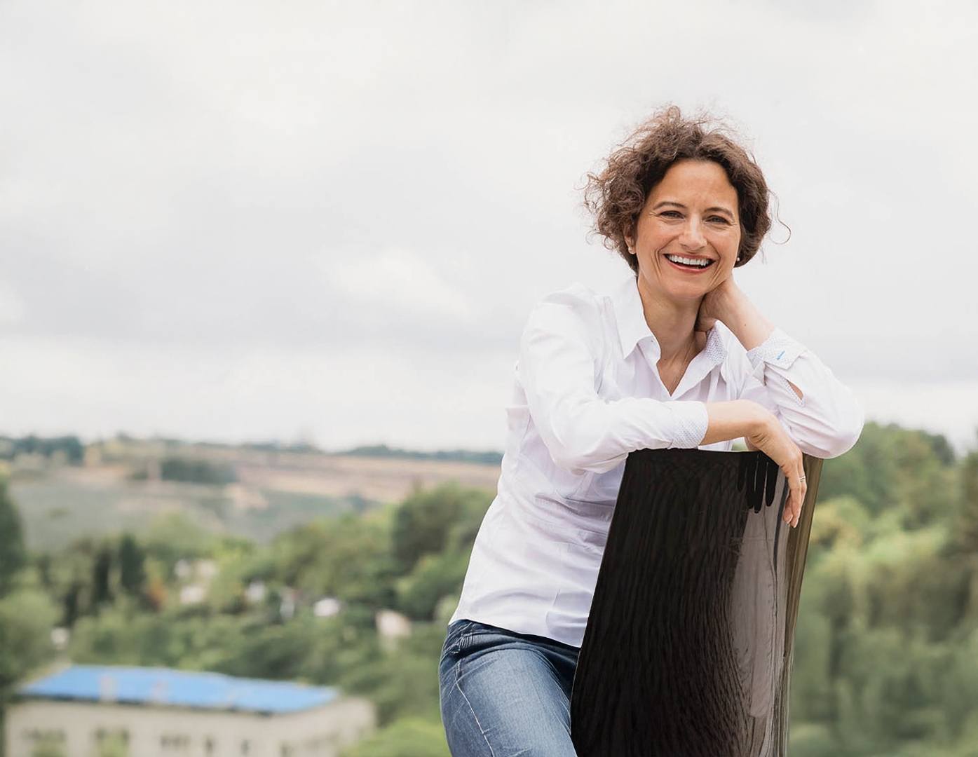 Dozentin der THWS lächelt entspannt im Außenbereich mit Blick über die Landschaft.