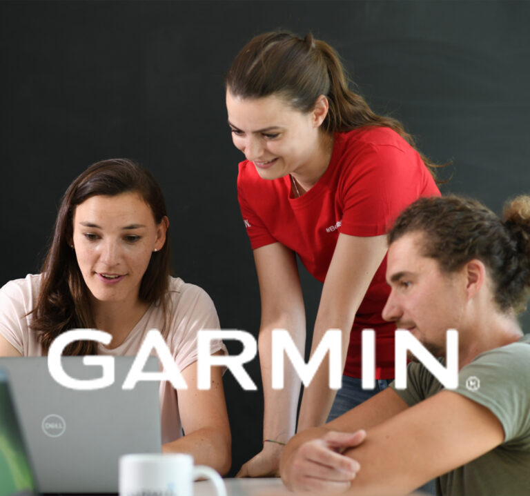 Teammeeting bei Garmin: Mitarbeitende arbeiten gemeinsam an einem Laptop