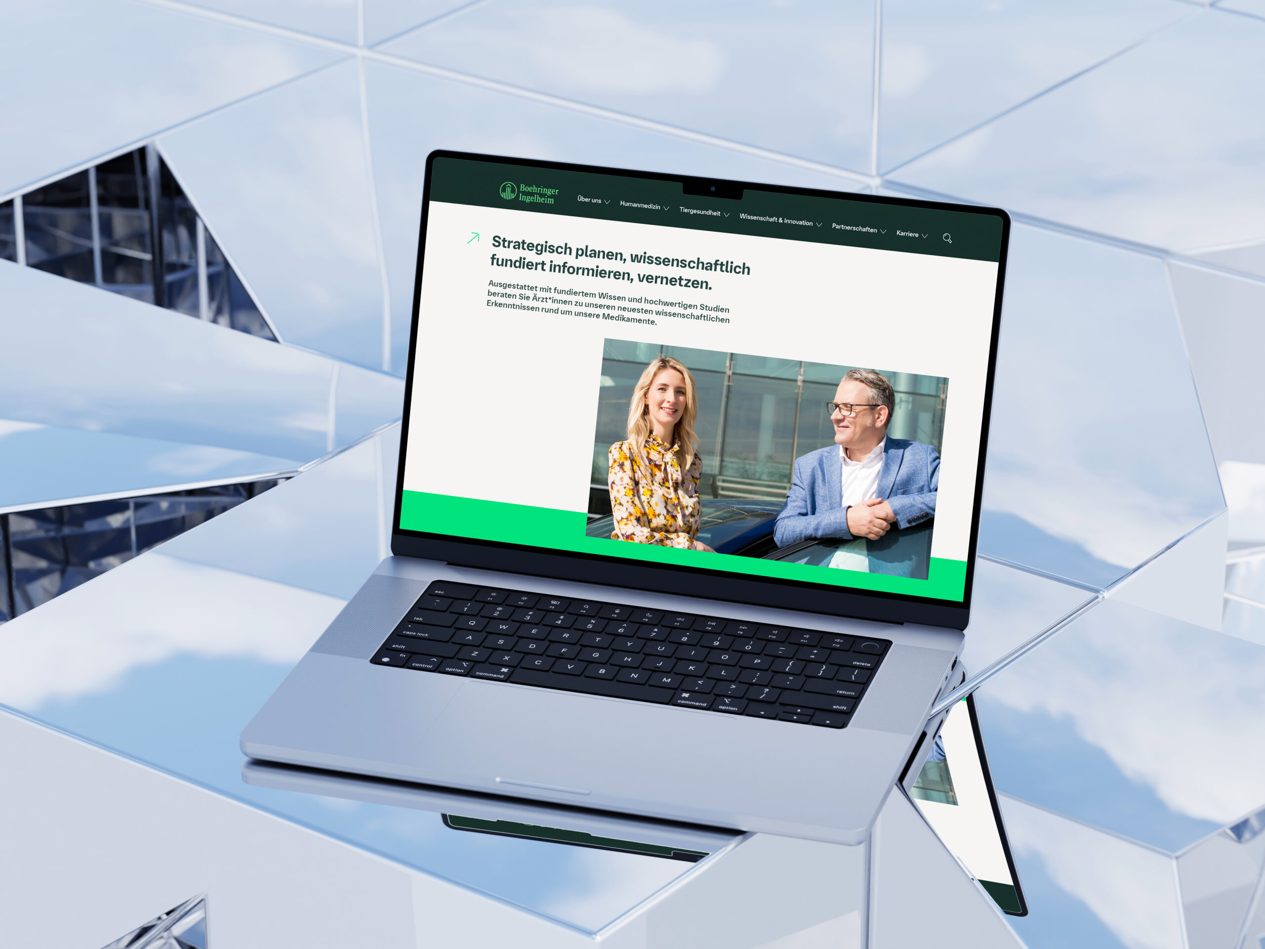Mockup eines Laptops, der eine Boehringer-Ingelheim-Karriereseite mit Mitarbeiterfoto anzeigt, platziert auf reflektierenden Glasflächen.