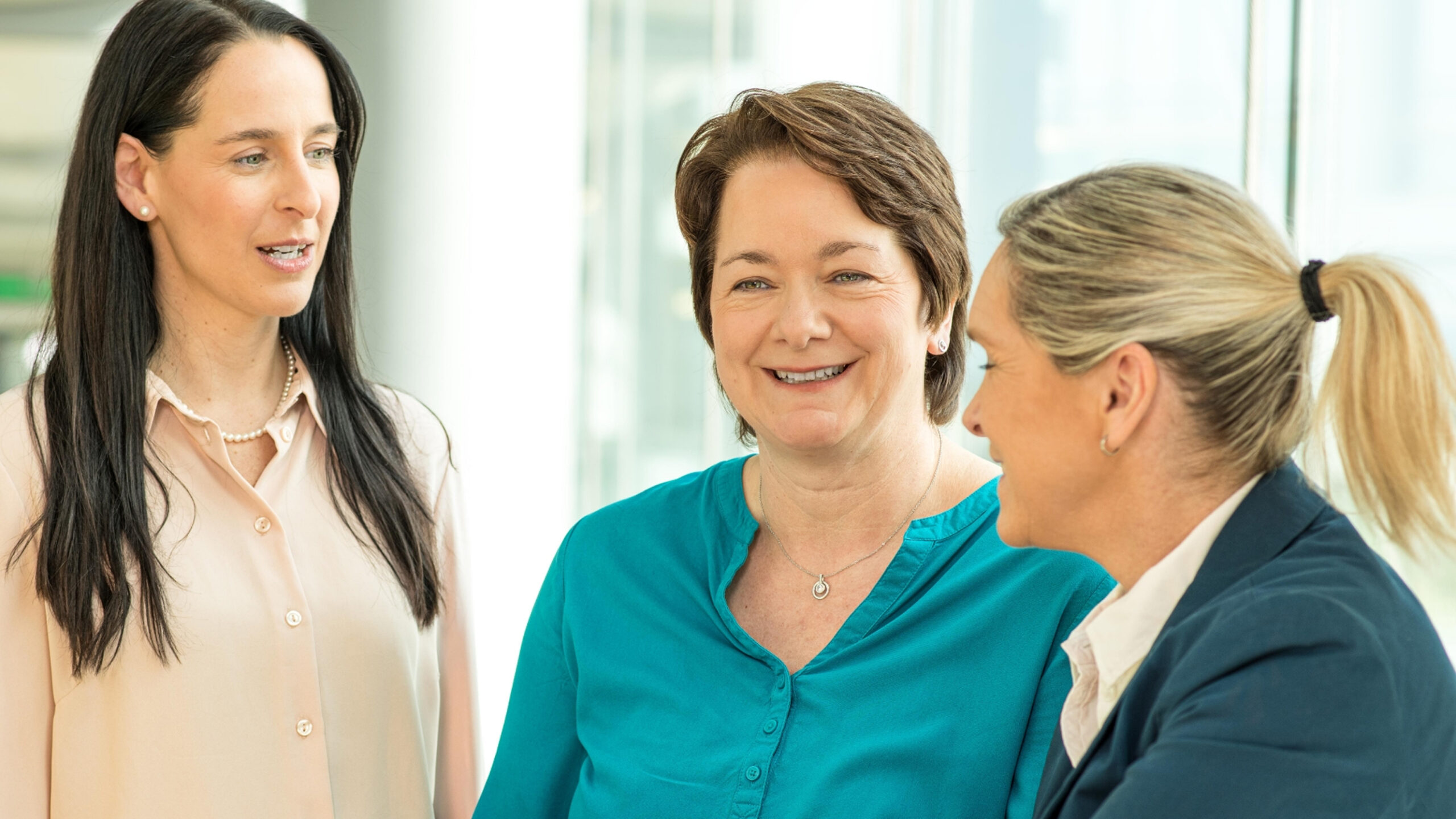 Drei Mitarbeiterinnen von Boehringer Ingelheim im Austausch in einem modernen Büro.