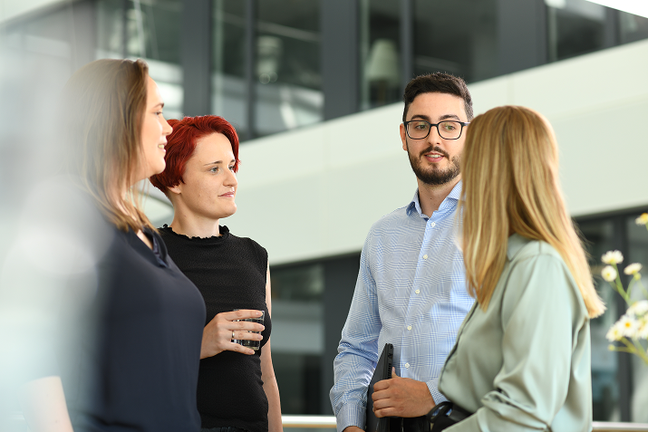 Gruppe von Mitarbeitenden bei Boehringer Ingelheim im Gespräch in einer modernen Büroarchitektur.