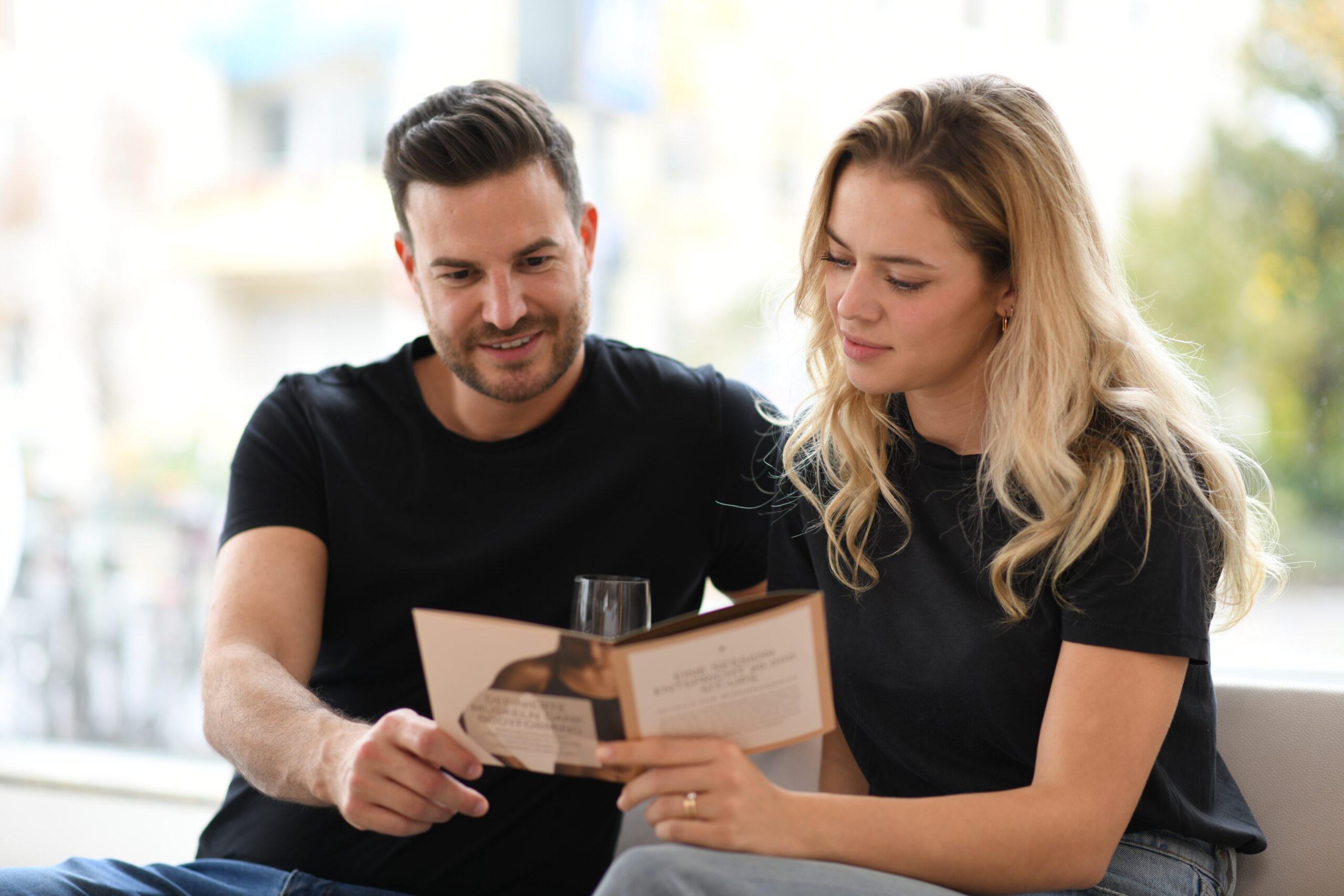 Paar schaut gemeinsam eine hochwertige Markenbroschüre an und spricht über Gestaltung und Inhalte.