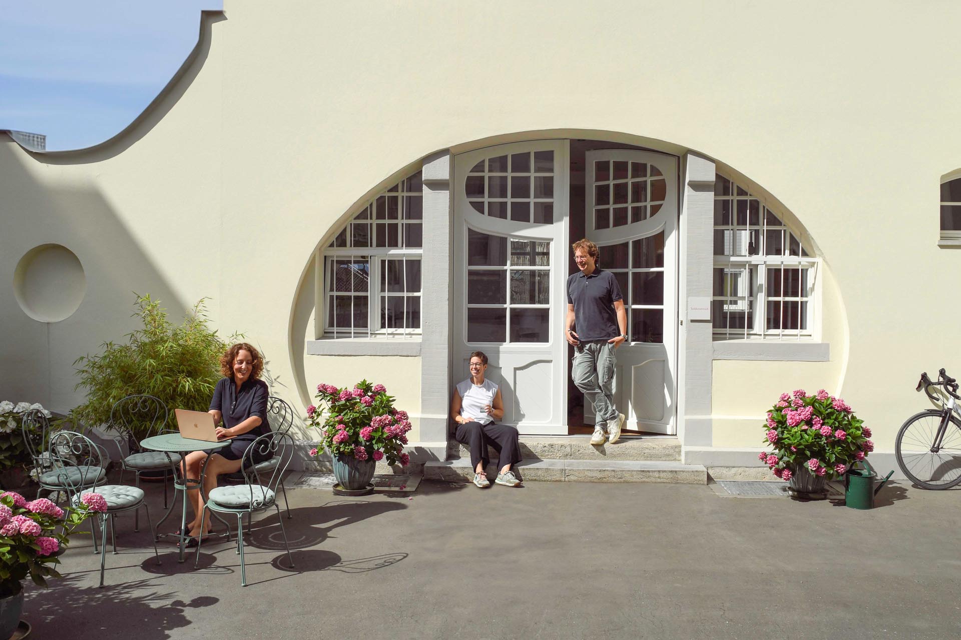 Teammitglieder der Agentur Heldenstreich im Innenhof vor dem Agenturgebäude, beim Arbeiten und Austausch in entspannter Atmosphäre – authentischer Einblick in die Arbeitskultur.