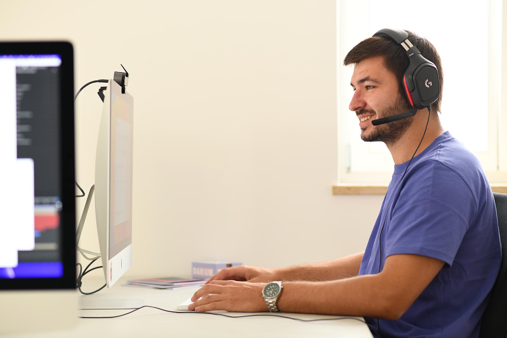 Mitarbeiter der Agentur Heldenstreich mit Headset am Schreibtisch, vertieft in ein digitales Meeting vor einem großen Monitor – moderner Einblick in die agile Arbeitsweise der Agentur.