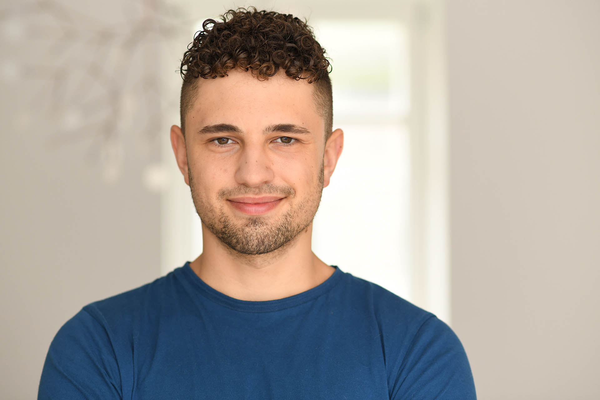 Junger Mitarbeiter der Agentur Heldenstreich lächelt in die Kamera im modernen Agentur-Umfeld.