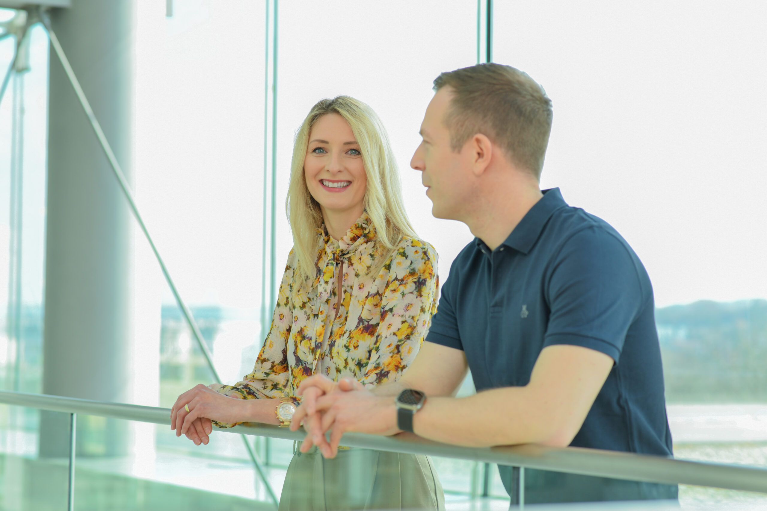 Zwei Mitarbeitende von Boehringer Ingelheim stehen in einem modernen, lichtdurchfluteten Gebäude und unterhalten sich freundlich.