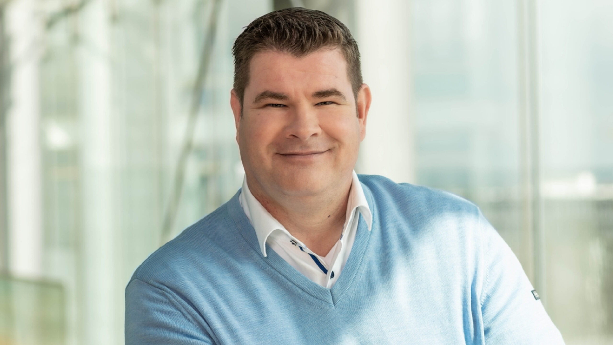 Porträt eines Mitarbeiters von Boehringer Ingelheim vor einem modernen Bürohintergrund.