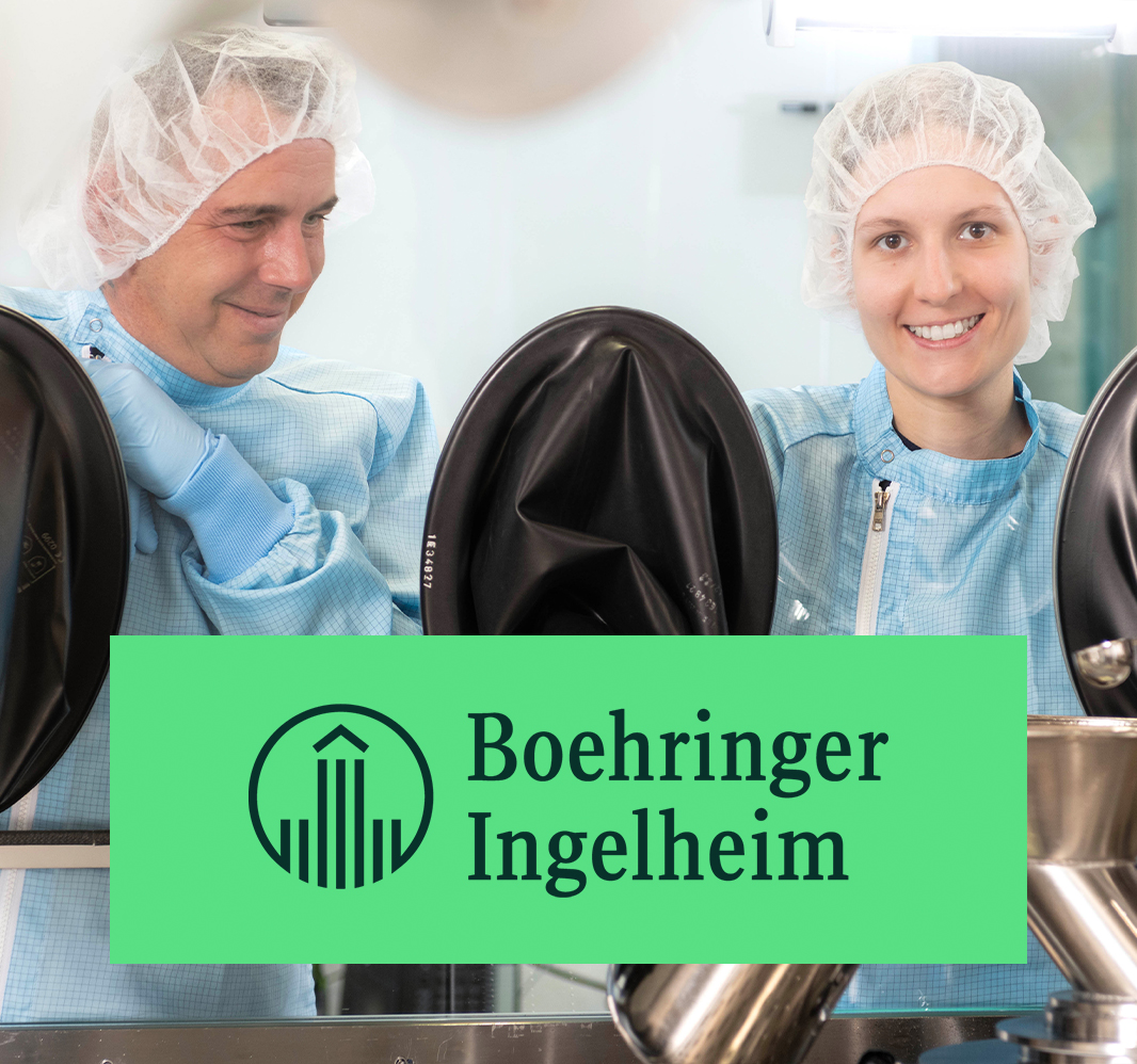 Mitarbeiterinnen und Mitarbeiter in steriler Produktionskleidung arbeiten an einem Reinraumarbeitsplatz bei Boehringer Ingelheim.