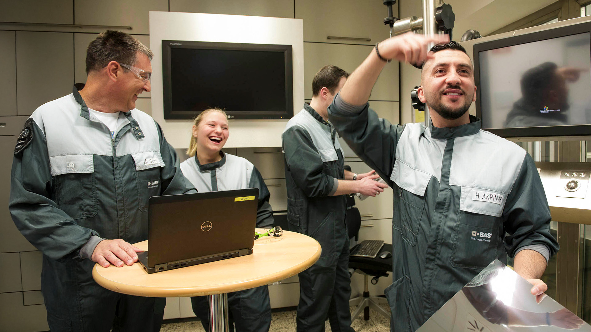 Mitarbeiterteam der BASF Coatings Würzburg arbeitet gemeinsam im Labor und lacht während einer Besprechung.