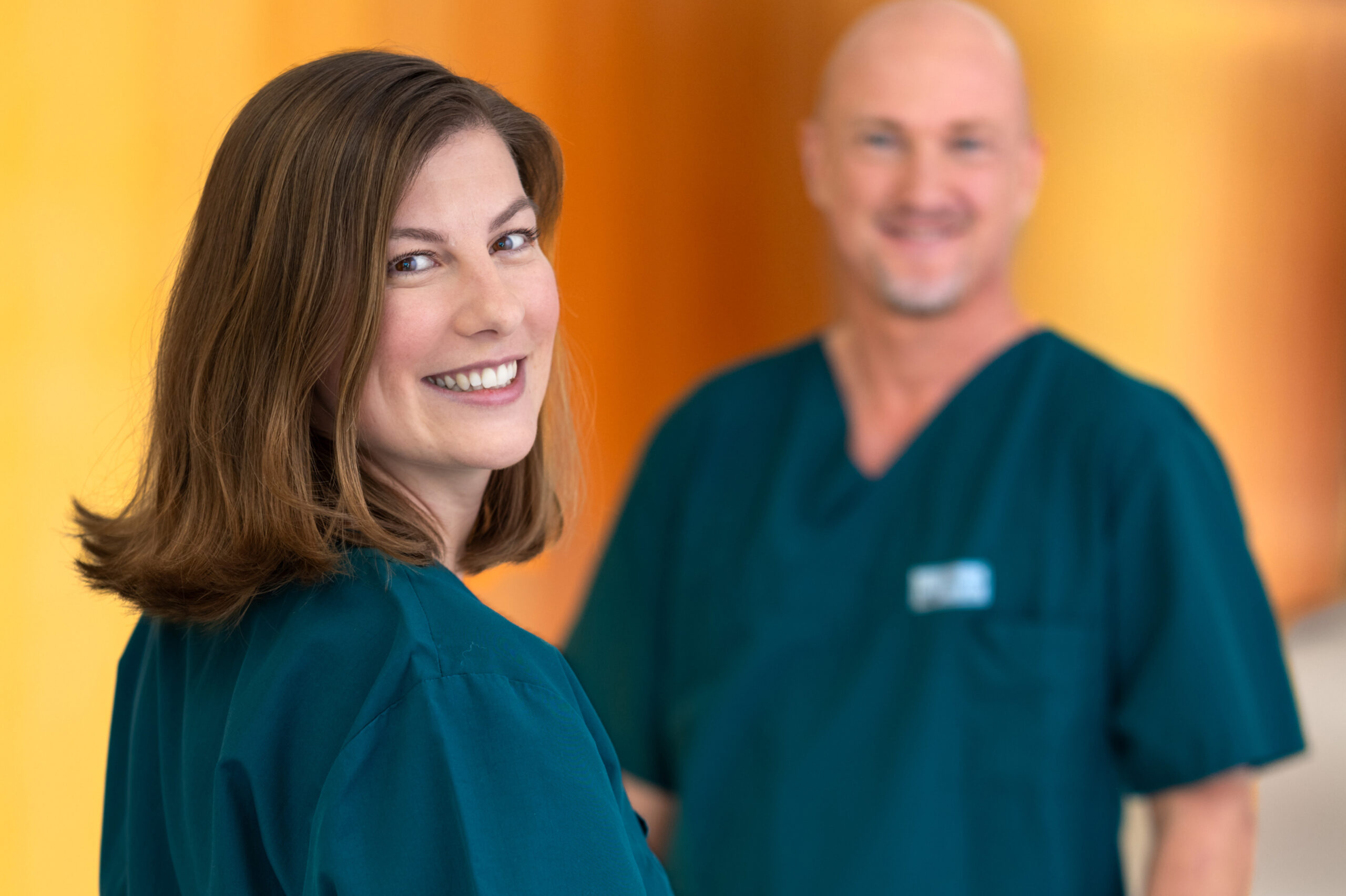 Pflegekraft lächelt in die Kamera, weitere Pflegekraft im Hintergrund – Fotoshooting im LMU Klinikum München