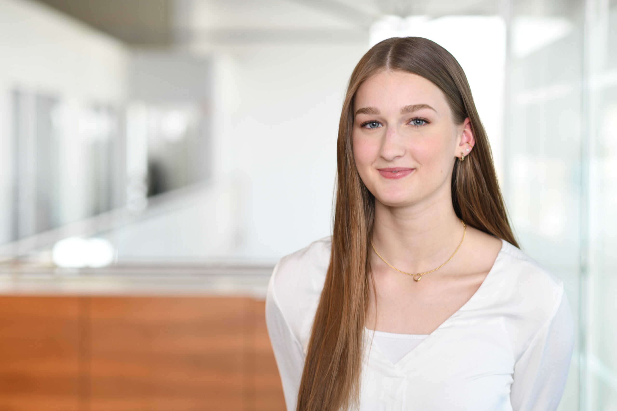 Junge Mitarbeiterin im Bürobereich eines Autohauses, freundlich lächelnd in die Kamera.