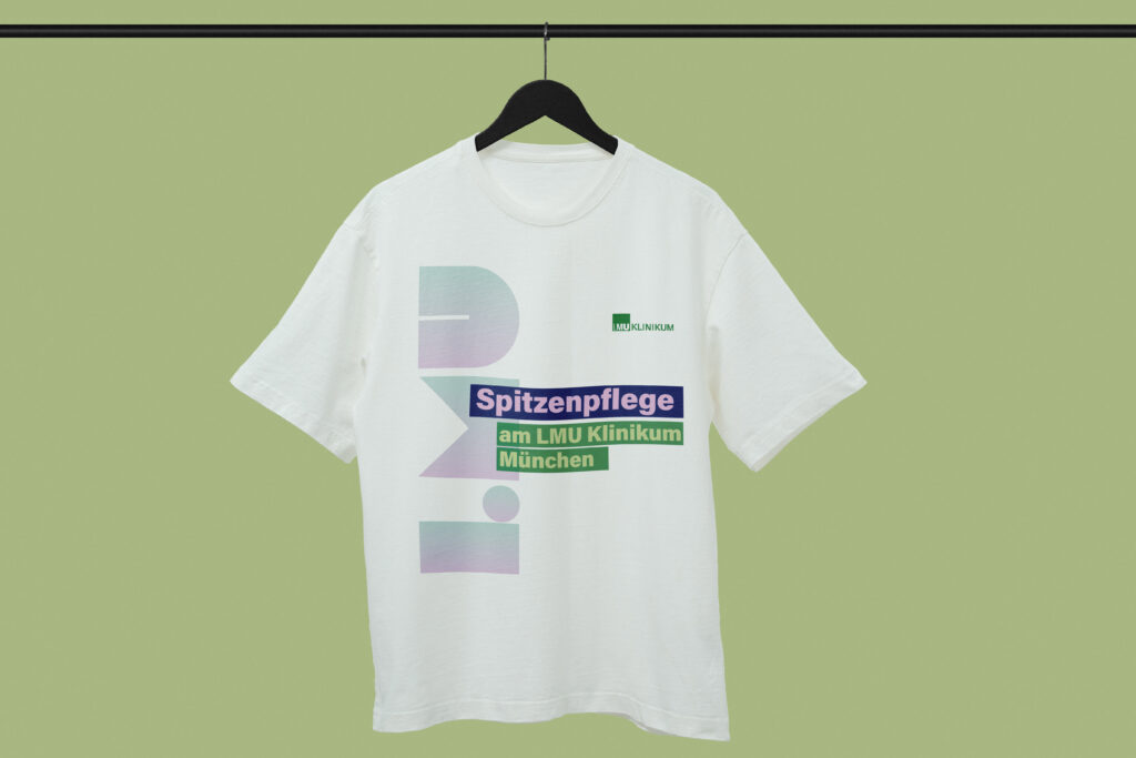 T-Shirt-Mockup mit dem Claim „Spitzenpflege am LMU Klinikum München“ im Corporate Design der Pflegekampagne.