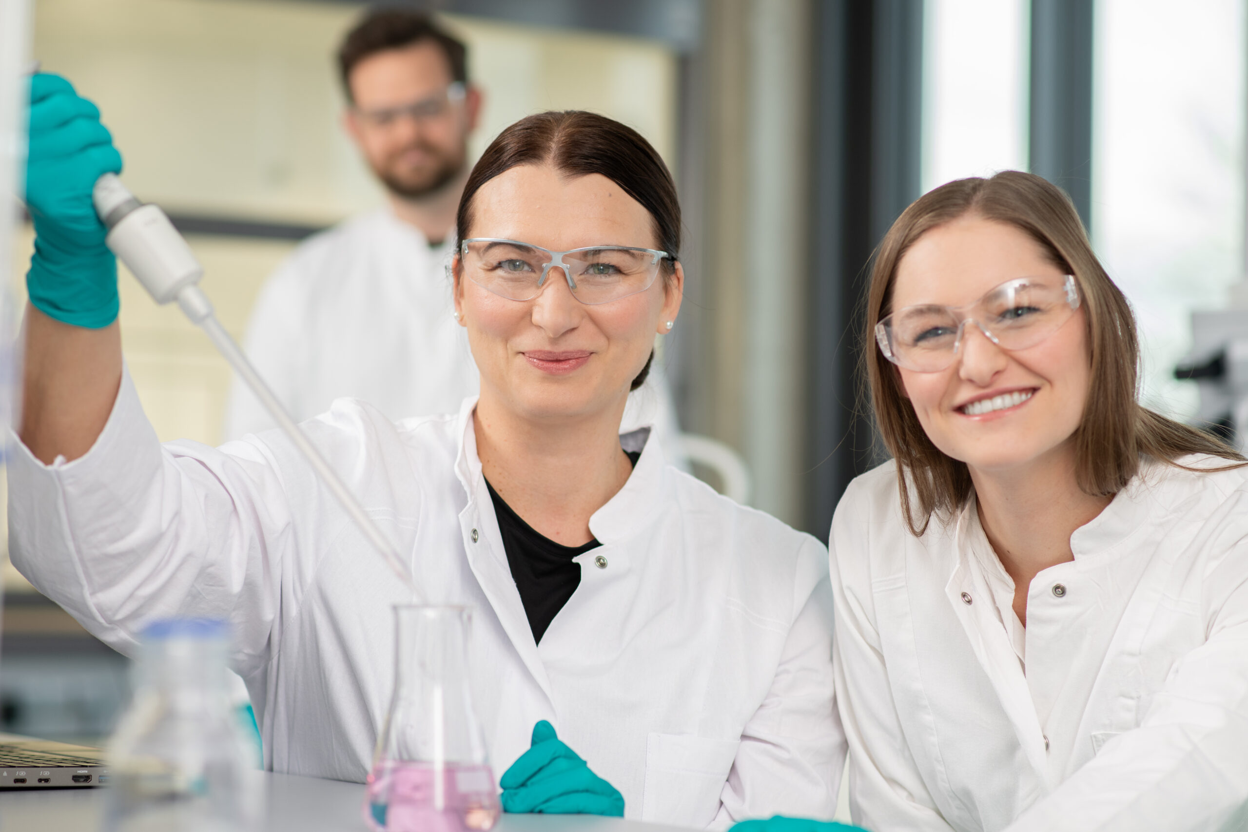 Mitarbeitende und Auszubildende bei AMW arbeiten gemeinsam im Labor und führen praktische Experimente durch