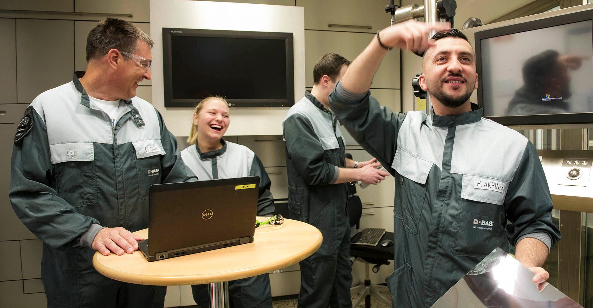 Mitarbeiterteam der BASF Coatings Würzburg arbeitet gemeinsam im Labor und lacht während einer Besprechung.