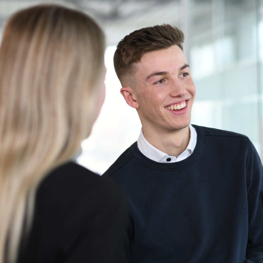 Junger Mitarbeiter von Widmann & Winterholler im Gespräch in einem modernen Autohaus