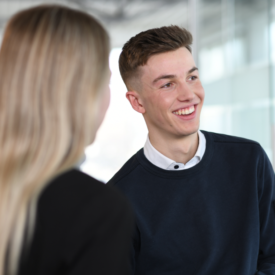 Junger Mitarbeiter von Widmann & Winterholler im Gespräch in einem modernen Autohaus