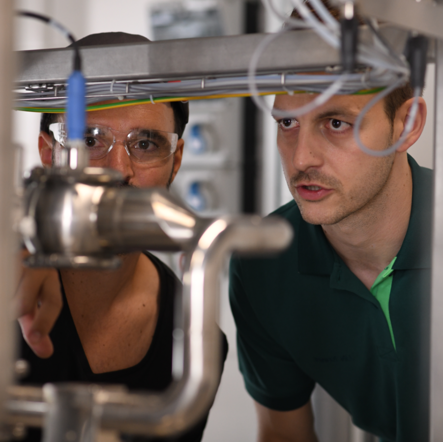 Zwei Mitarbeitende von Boehringer Ingelheim prüfen eine technische Anlage in der Produktion.