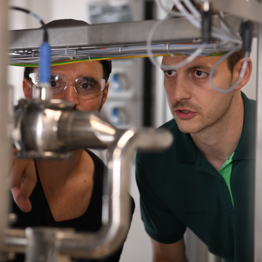 Zwei Mitarbeitende von Boehringer Ingelheim prüfen eine technische Anlage in der Produktion.